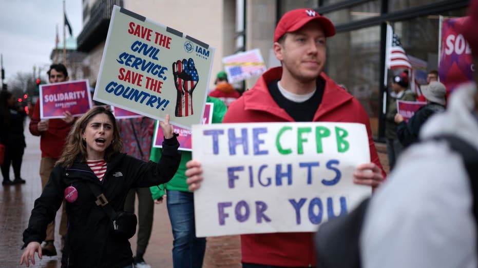 Activists participate in a rally outside while holding signs